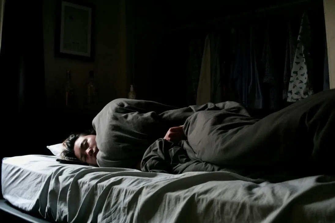 Person lying awake at night, experiencing sleep disturbances as signs of burnout and mental health red flags