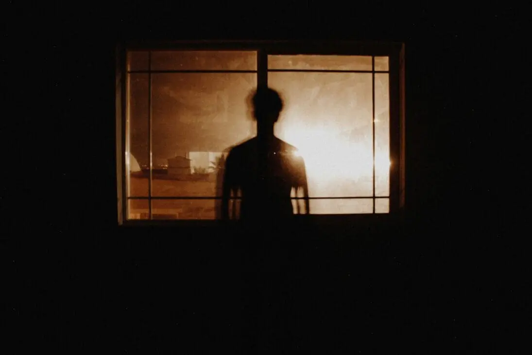 Faceless blogger reflecting quietly near a window