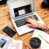 A young woman sitting at a cozy desk, typing on her laptop while brainstorming ideas for her blog