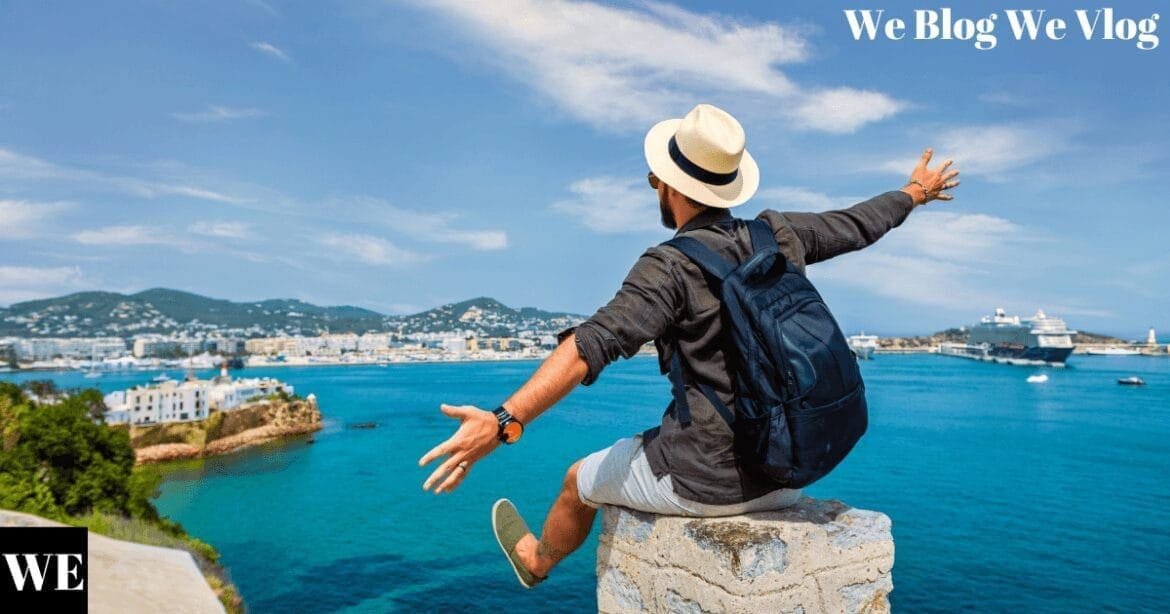 A man standing on a cliff edge with his arms outstretched, overlooking a vast, calm ocean under a sunny sky, evoking freedom and adventure.