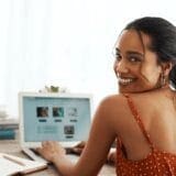 Woman smiling over her shoulder while using a laptop.