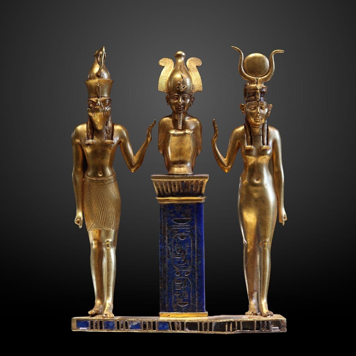 The family of the Egyptian god Osiris. Osiris on a lapis lazuli pillar in the middle, flanked by Horus on the left and Isis on the right. Photo: Wikimedia Commons