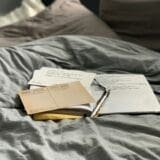 A cozy flat lay of journals, postcards, and a pen, representing a peaceful space for journaling and emotional healing through self-reflection.