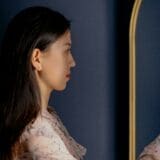A woman practicing morning affirmations in the mirror to build self-love and confidence.