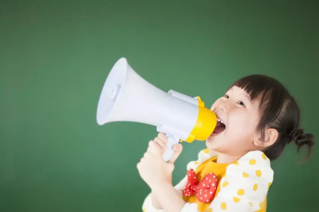 A toddler with a megaphone playfully shouts a fun metaphor for how bold humor helps brands grab attention and connect with audiences.