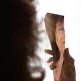 Person looking at their reflection in the mirror, symbolizing emotional growth and trauma recovery through self-awareness.