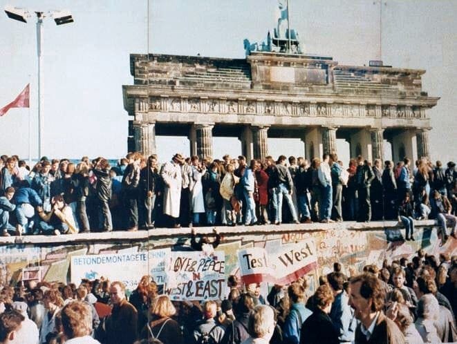Germans stand on top of the Wall in front of the Brandenburg Gate, before this section was torn down on 9 December 1989. Photo: Wikipedia