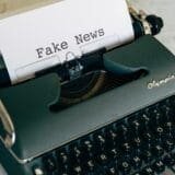 A sheet of paper with the words "Fake News" typed on it, inserted into a vintage Olympia typewriter.
