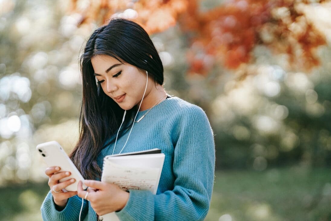 Happy woman browsing pop culture predictions 2025 on her smartphone via social media.