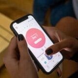 Close-up of a person using a mobile app on a smartphone to track their menstrual cycle, showing "Day 7" of the current cycle on the screen.