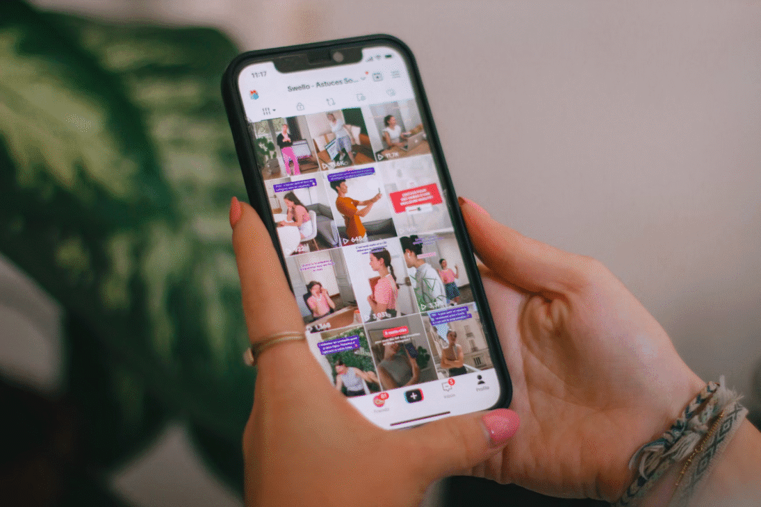 A hand holding a smartphone while scrolling through the TikTok app.