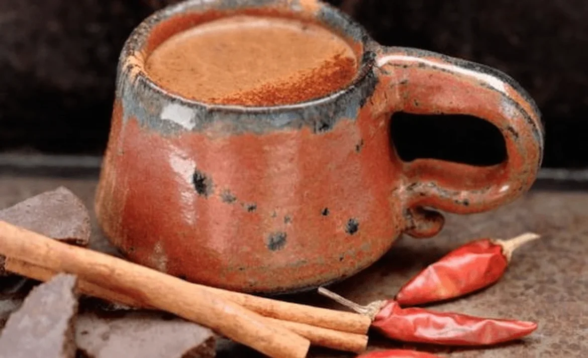 Traditional Mayan xocolatl served in a clay cup with a red chili pepper, reflecting its original bitter and spiced flavor relating to the oldest recipes in the world