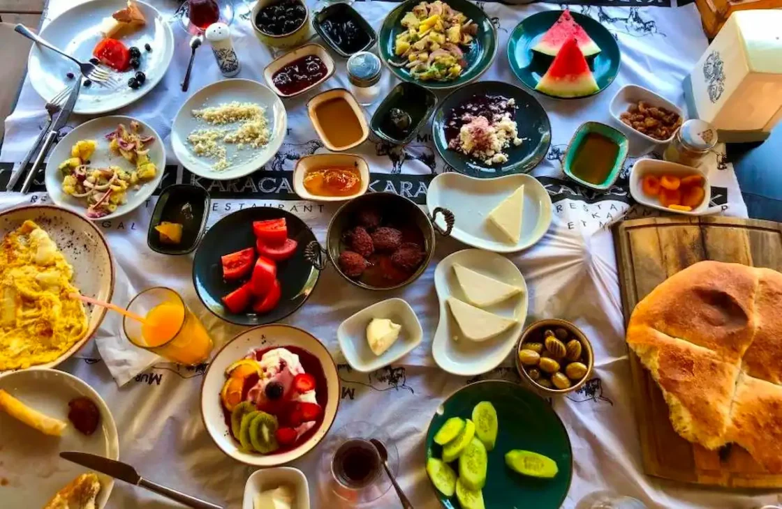 Traditional Turkish breakfast spread with cheeses, olives, eggs, bread, and tea.