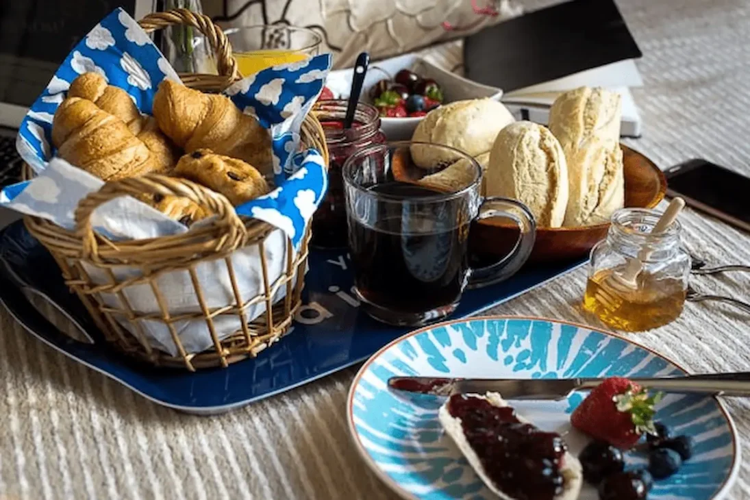 French breakfast featuring croissant, buttered baguette, jam, and café au lait.