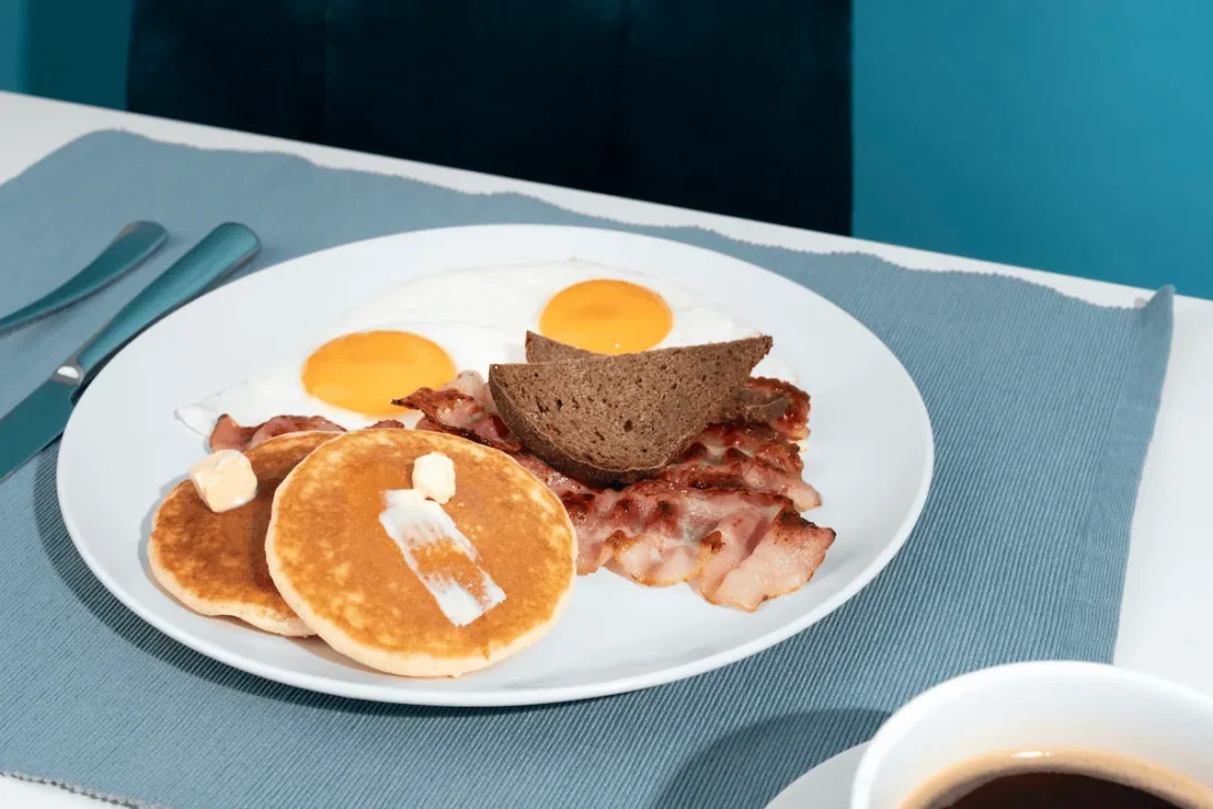 traditional breakfast around the world with stacked pancakes, fried eggs, and crispy bacon.