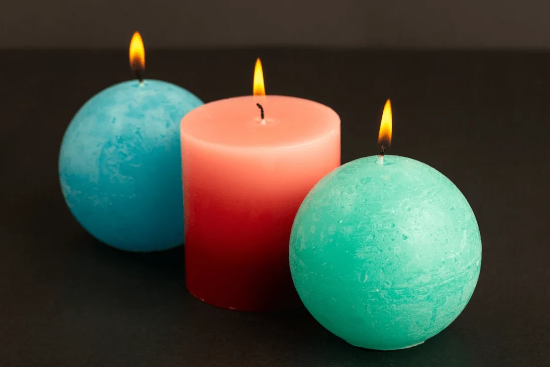 Blue, red, and green candles lit together, symbolizing the connections between life, death, and renewal.