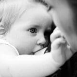 Black and white photo of a mother breastfeeding her baby, highlighting bonding and nurturing moments.
