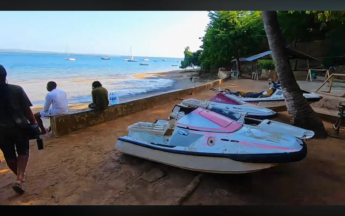 Small white jetski-style motorboats lined up along Tanga’s coast at sunrise.