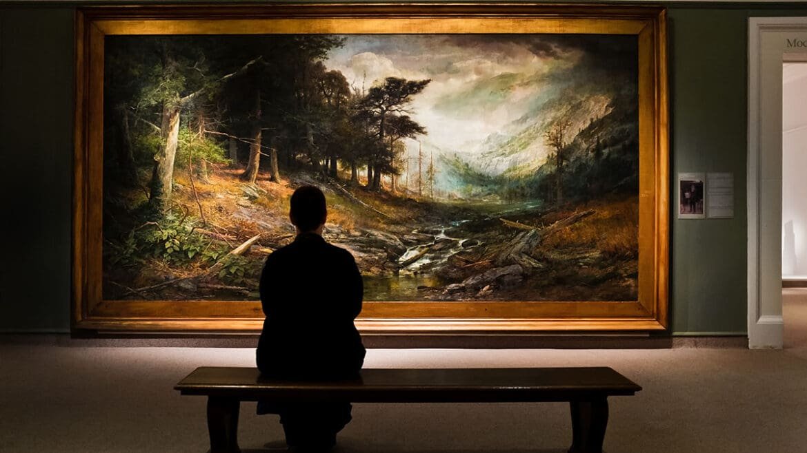 Man sitting on a museum bench, thoughtfully observing a large painting to practice slow and mindful art viewing.