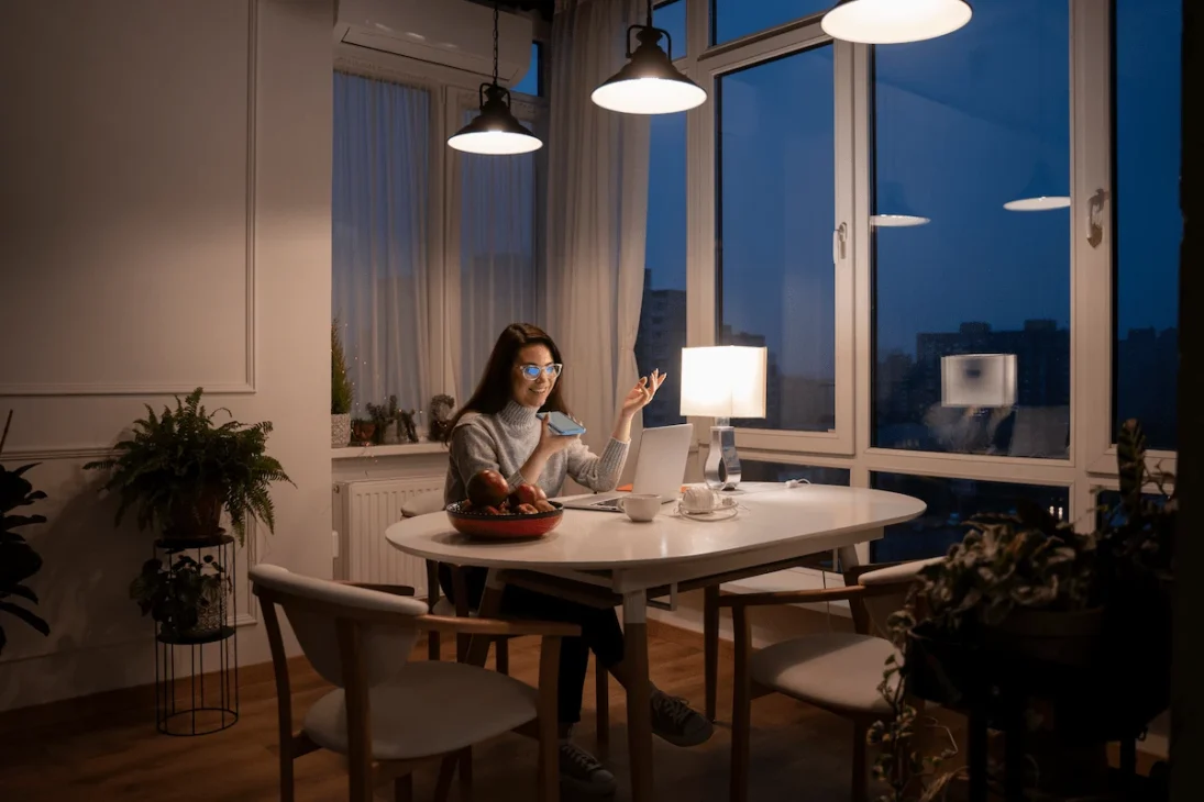 A smiling woman working from home on her laptop in a bright, comfortable room.