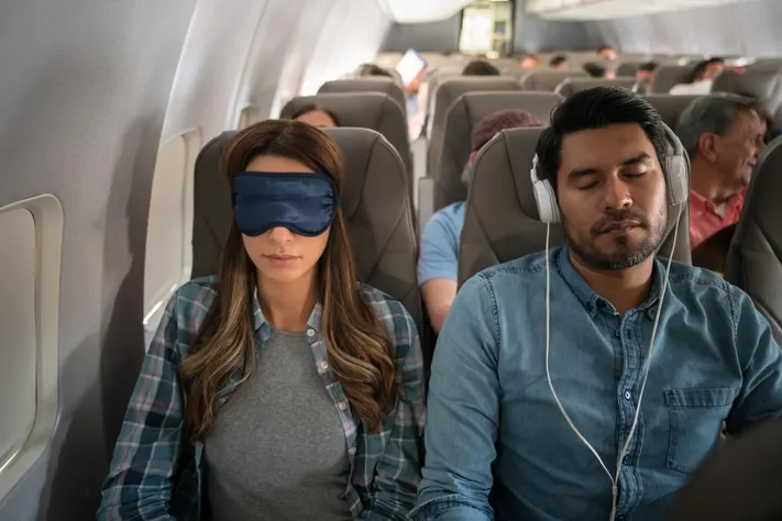 Jet lag tips foe traveler managing cabin light exposure during a long flight to reduce jet lag.