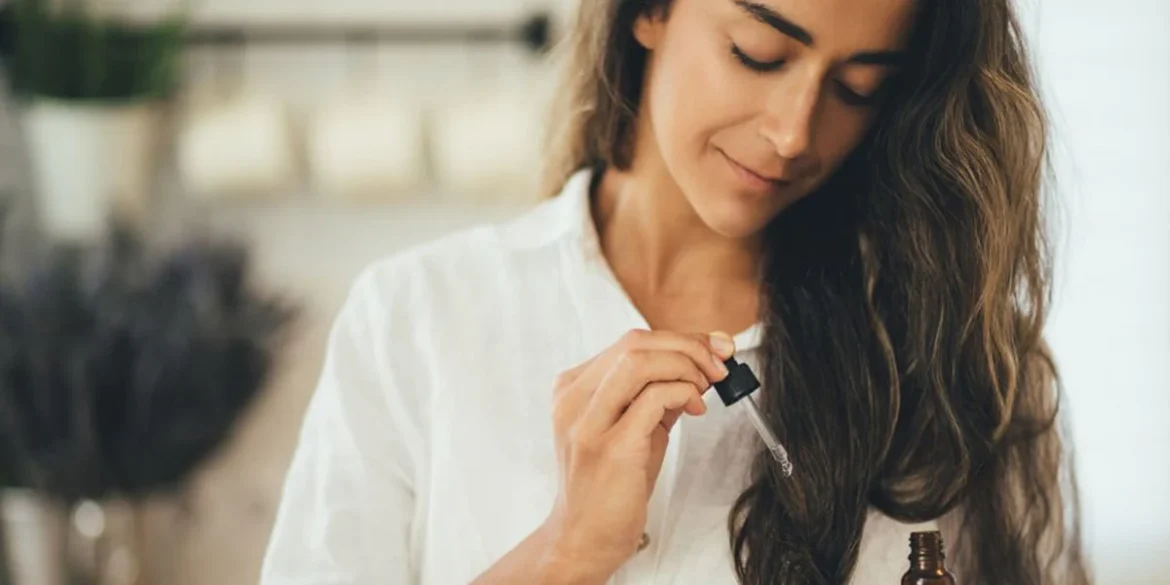 Close-up of a woman applying anti-frizz hair serum to protect her hair from sun damage during vacation.