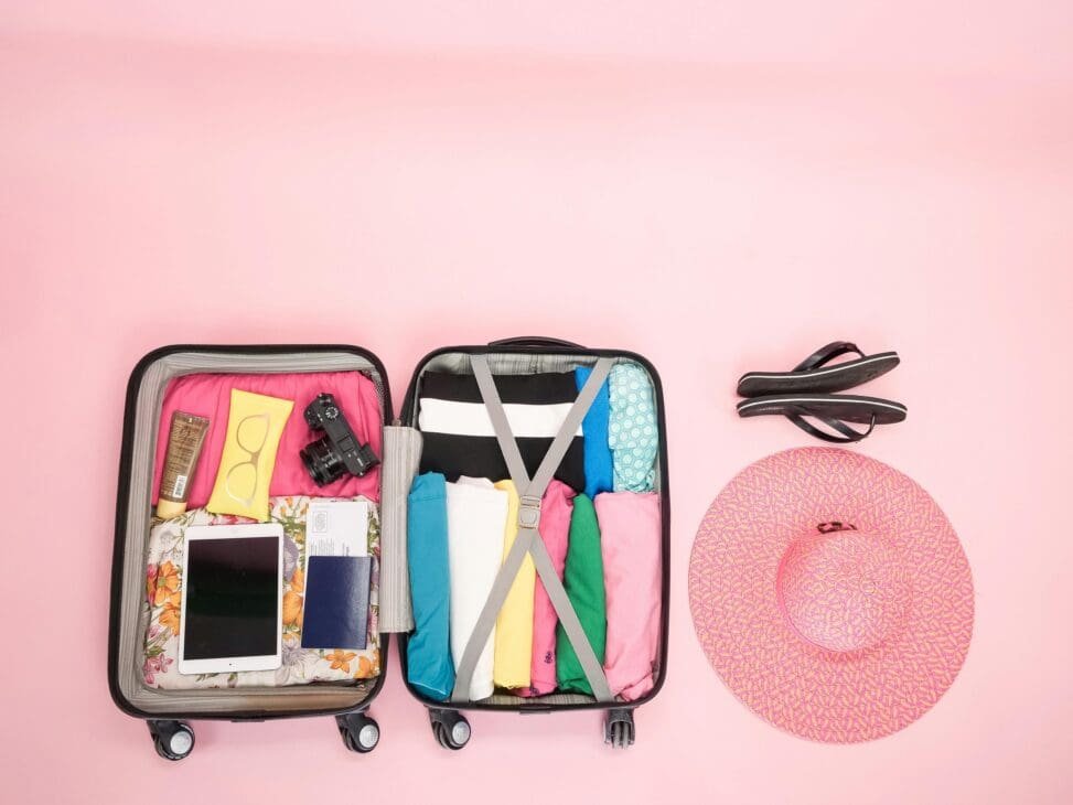 Flat lay of a pre-packed travel outfit checklist including tops, bottoms, shoes, accessories, and a portable steamer.
