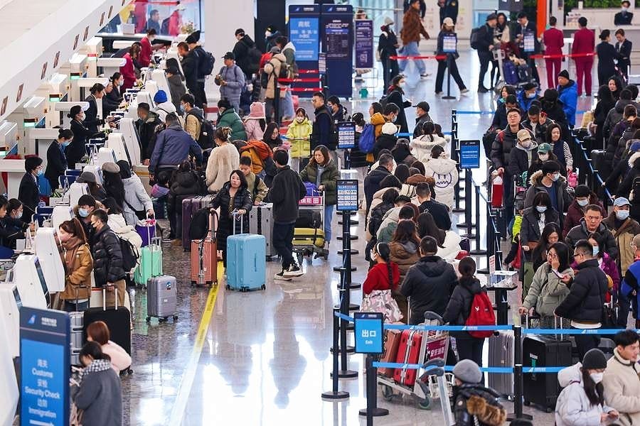 Crowded international airport check-in area during peak global events travel season, with long queues of travelers and luggage reflecting holiday travel demand.