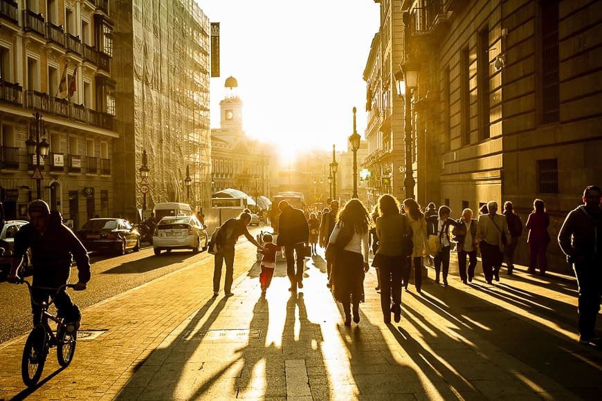 Empty city street at golden hour with reflections on wet pavement and leading lines, creating a cinematic urban photography scene.