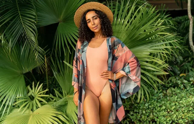 swimsuit guide of woman confidently standing poolside in a flattering swimsuit, smiling and relaxed under the sun.