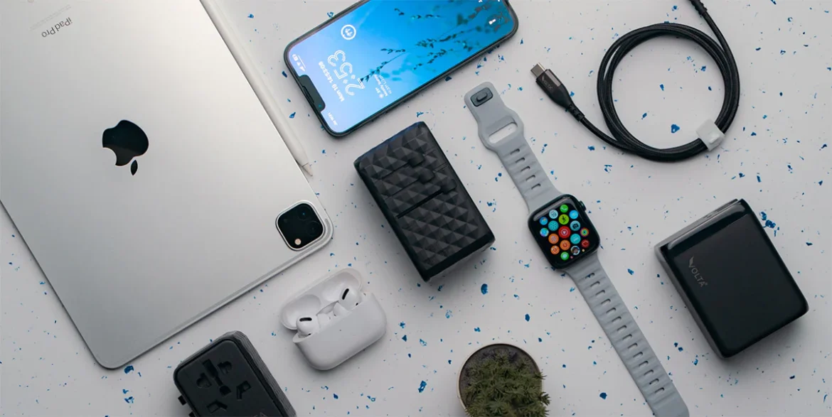 Flatlay of travel tech items including a power bank, eSIM QR code, compact camera, smartwatch, AirTag, and a sleek travel wallet arranged neatly on a neutral background.