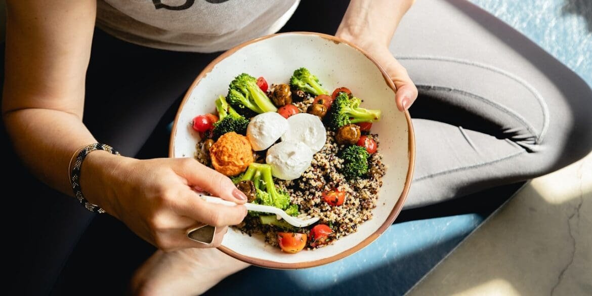 A person arranging a balanced meal with protein, carbs, healthy fats, and vegetables