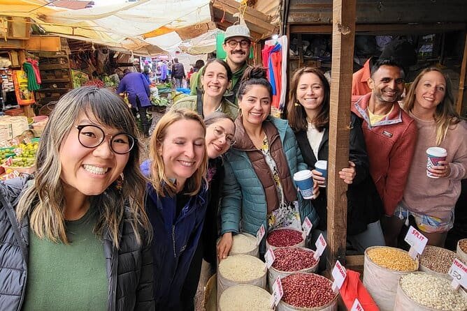 Diverse travelers taking photos together in a bustling Kenyan market, surrounded by colorful stalls and local crafts.