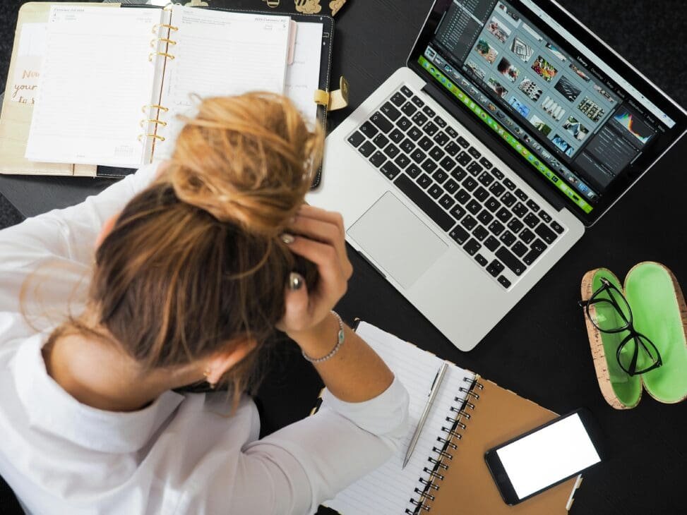 A person staring at a cluttered desk with unfinished tasks, looking overwhelmed but determined to refocus.