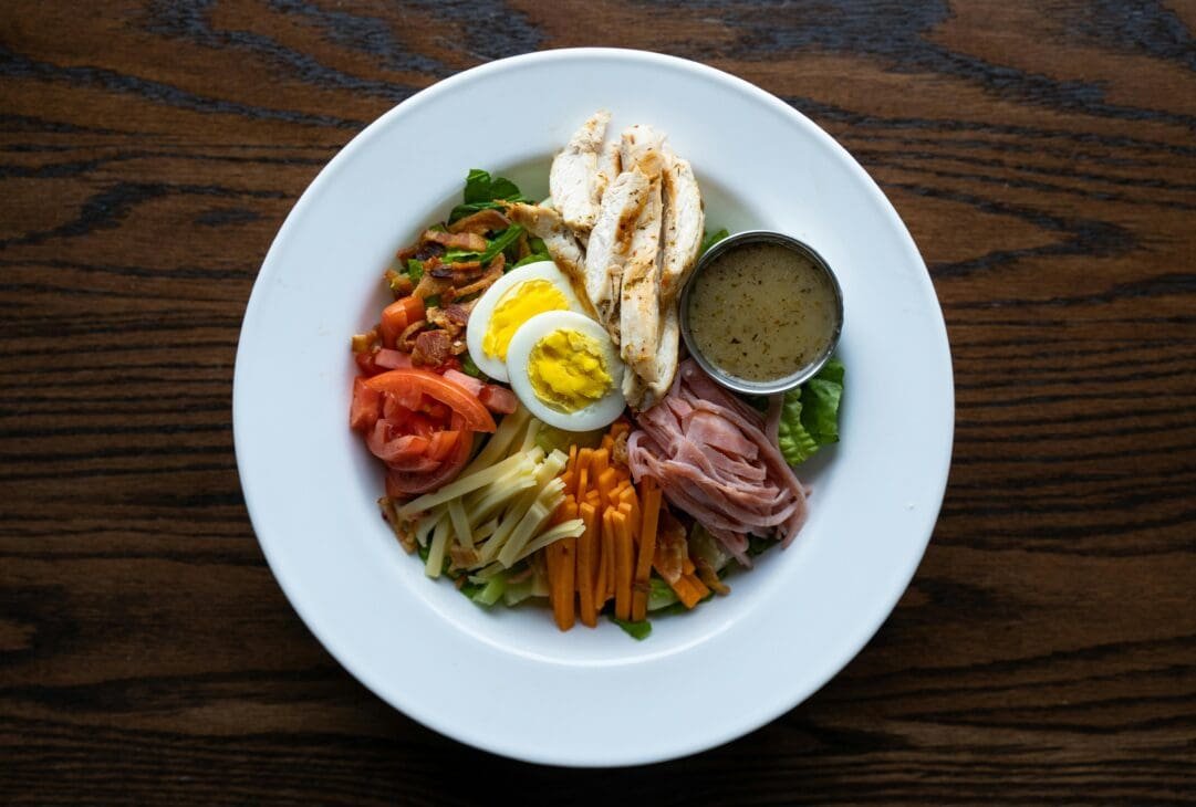 Protein-rich foods including chicken breast, salmon, eggs, Greek yogurt, lentils, and tofu arranged on a plate to illustrate protein as the body’s building blocks.