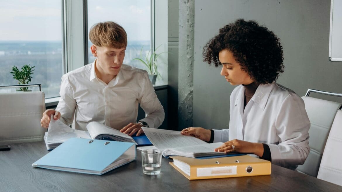 Two colleagues sitting at a table, reviewing a checklist together, symbolizing accountability and collaborative follow-through.