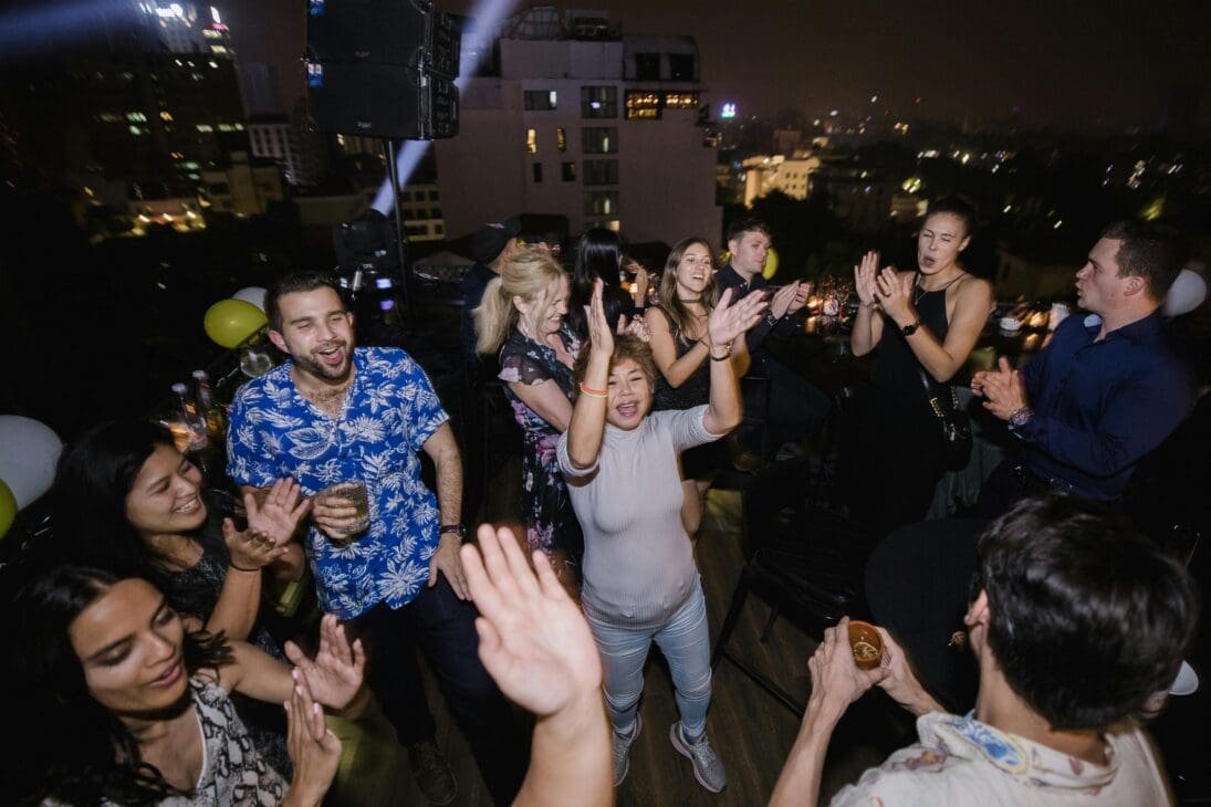 Locals and travelers enjoying live music and dancing at a lively Nairobi rooftop bar at night.