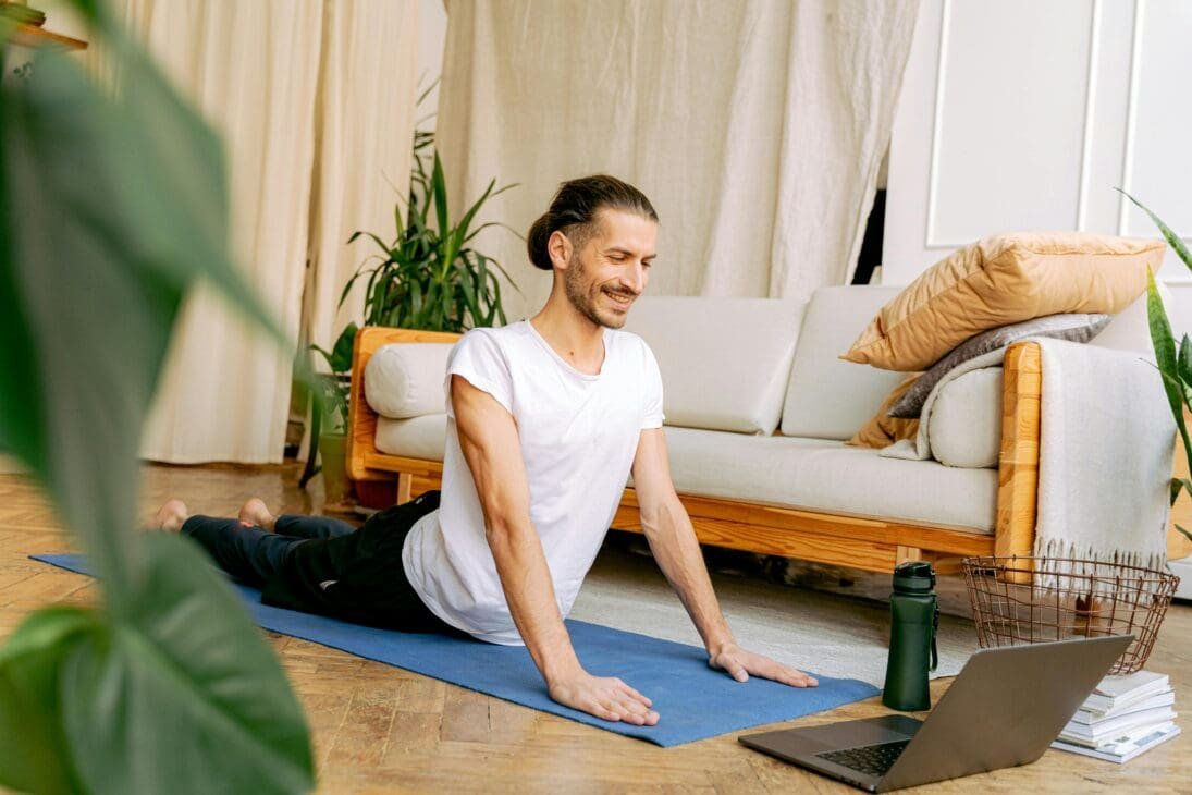A person stretching after a virtual meeting, with sticky notes and a laptop nearby, illustrating integrating movement into daily work-from-home routines.