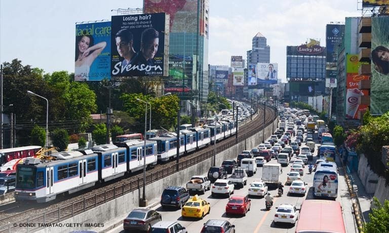 Heavy traffic in Metro Manila with cars, jeepneys, buses, and motorcycles navigating a busy urban street during rush hour.