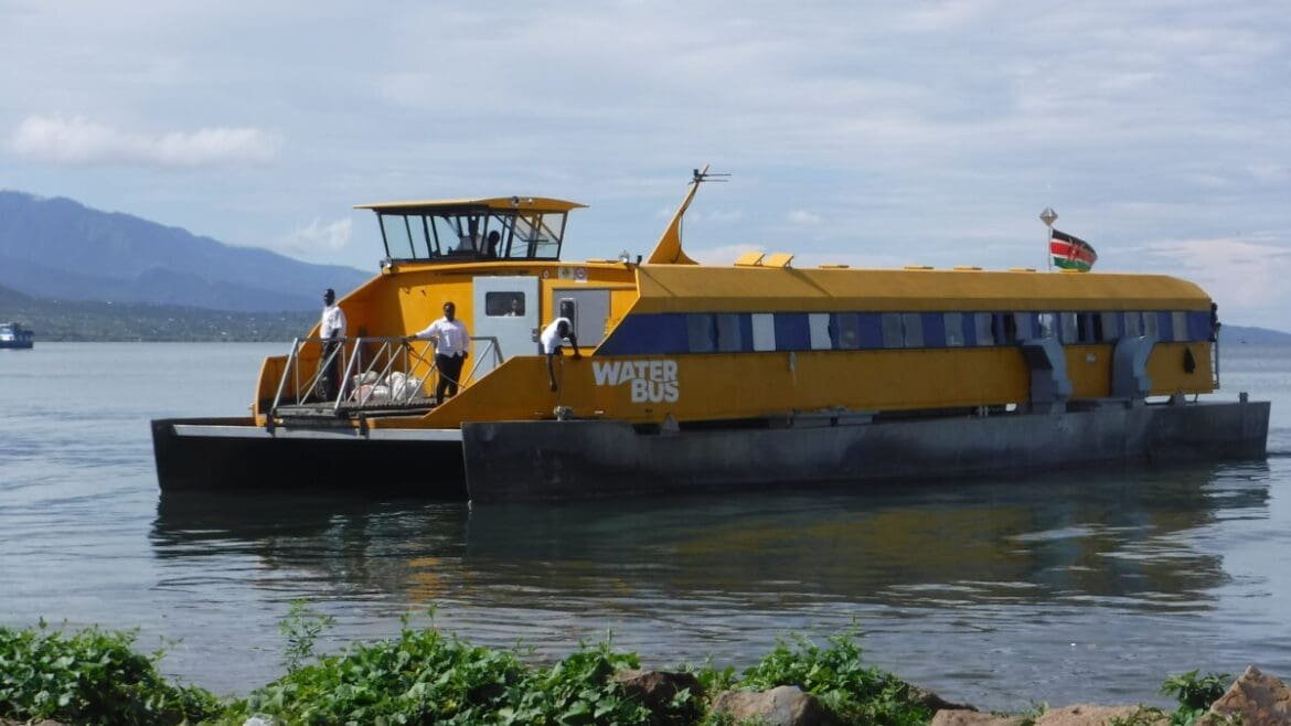A passenger ferry gliding across the calm waters of Lake Victoria under a partly cloudy sky.