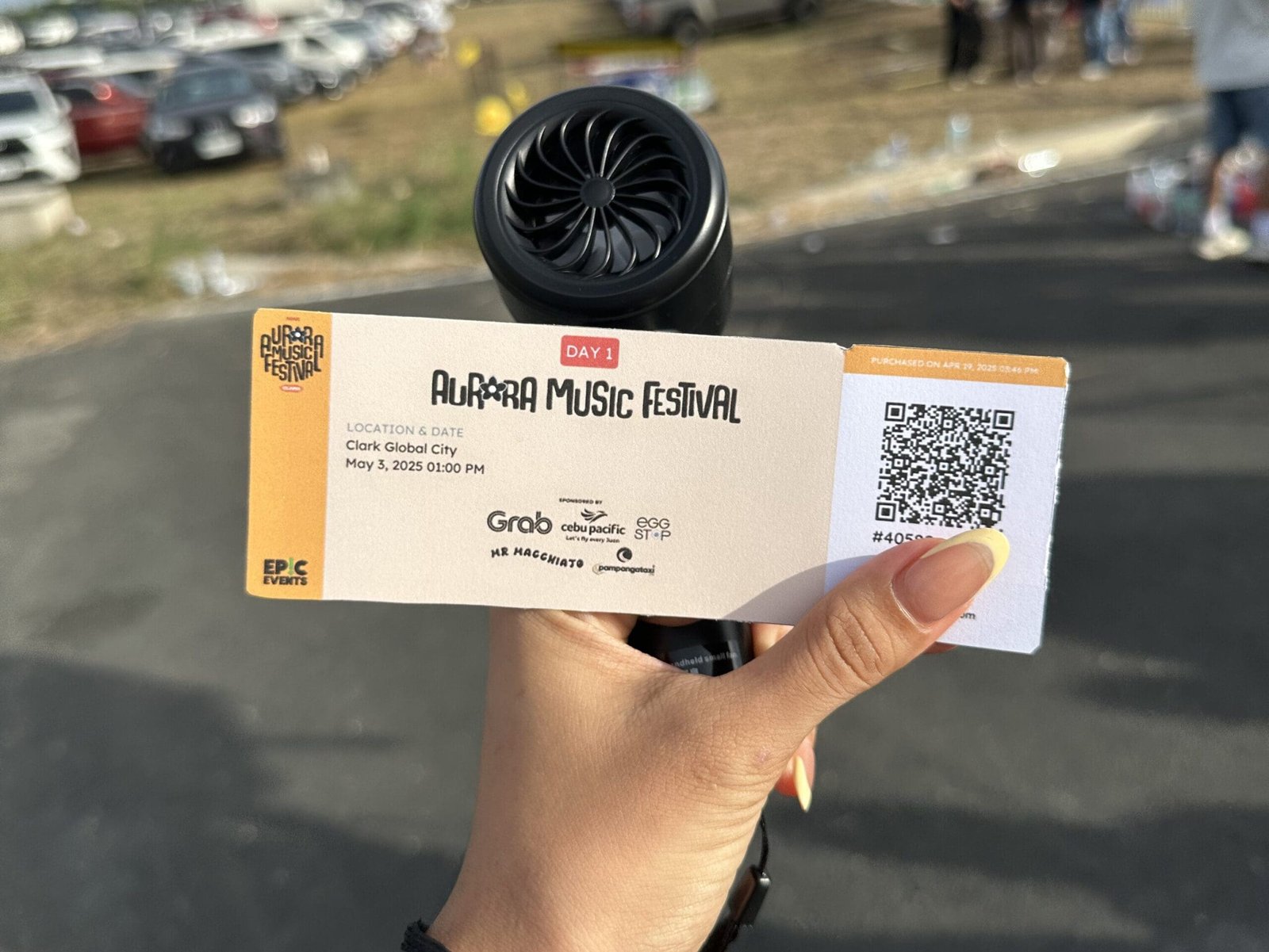 Hand holding an Aurora Festival ticket at the Clark, Pampanga venue, ready for the night of live Filipino music and adventure.