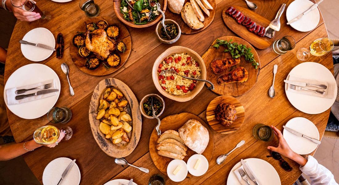 Group of people enjoying a table filled with diverse traditional African dishes, sharing food and conversation.