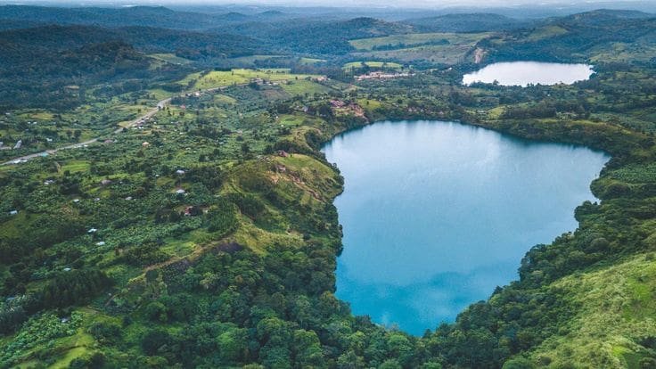 Peaceful Ugandan landscape with misty forests and still water, illustrating why wellness travelers are drawn to low-density, nature-based destinations.