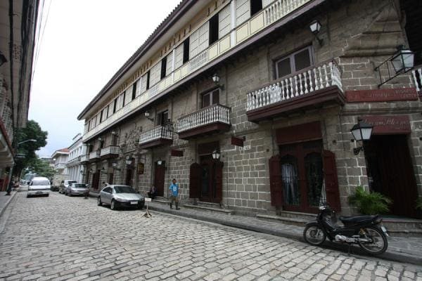 Visitors walking along cobblestone streets in Intramuros, Manila, surrounded by colonial-style houses.