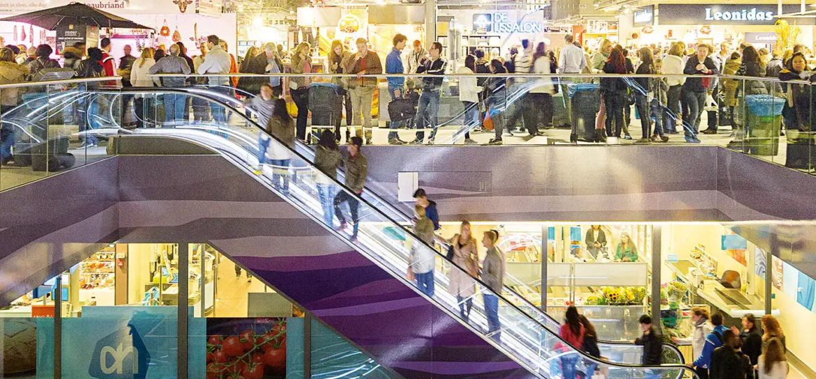 Wide interior view of a Manila mall with directional signs, escalators, and crowds moving between food courts, transport access points, and retail shops.