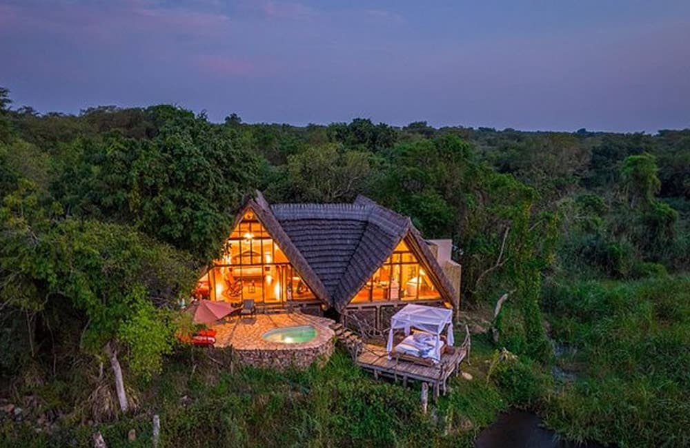 The Nile Safari Lodge in Uganda, a luxury eco-lodge surrounded by lush forest and a lake, exemplifying nature-based wellness travel.